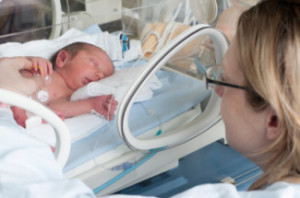 mother looking in at infant in incubator