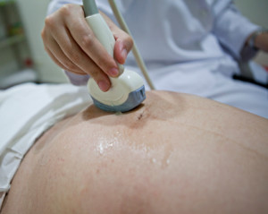 Obstetrician examining pregnant belly by ultrasound