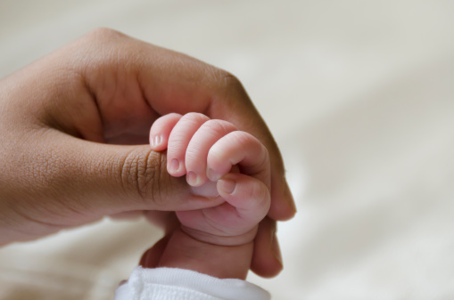 baby fingers curled around adult thumb