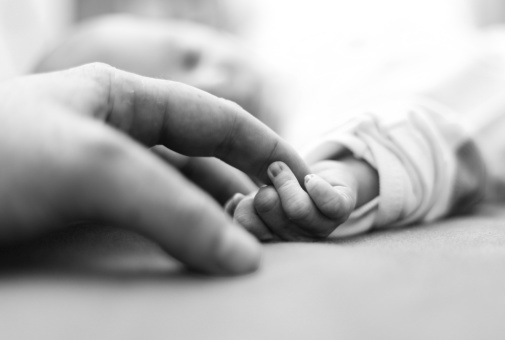 baby reaching toward adult finger